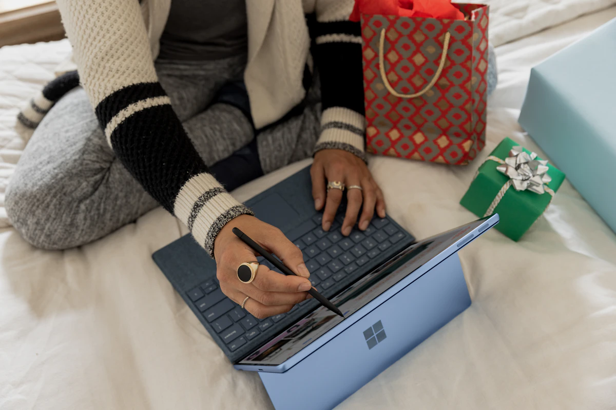 Persona consultando una computadora portátil junto a bolsas y paquetes de compras