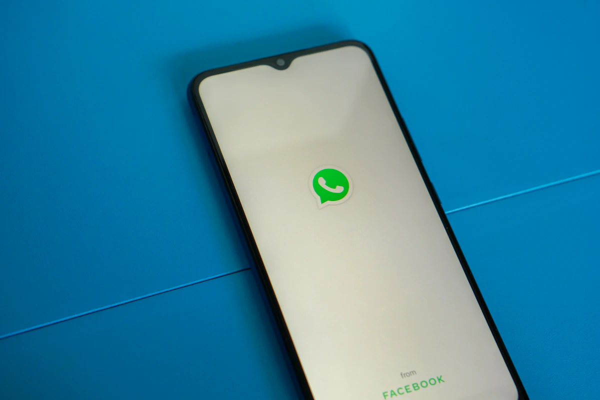 Teléfono con el logotipo de WhatsApp sobre una superficie azul